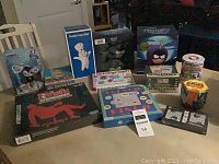Photo showing 12 assorted toys, games, and trading cards including Risk Office Politics board game, Desert Storm cards, Pillsbury Doughboy Giggle Bank, Poopsie Unicorn Poop, Spirograph, and other boxed items.