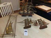 Overview of three nautical decor pieces on table including wooden sailing ship, copper bridge art and Mario Jason copper art