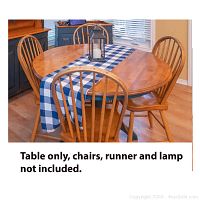 A photo showing the 46 inch round wooden kitchen table with a blue and white checkered runner and four chairs around it. Table expands by adding a removable leaf. Chairs, runner, and lamp are not included.