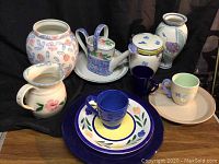 Photo showing all ceramic items together including vases, pitchers, plates, mugs, and canister