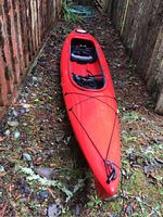 Full-length view of red kayak outdoors between wooden fences