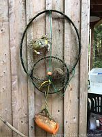 Crab net yard art featuring attached crabs and buoy, hanging on wooden wall.