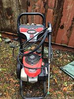 Front view of Simpson pressure washer unit showing frame, engine, hose and wand attachment
