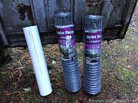 Two rolls of 50 feet by 28 inches galvanized steel garden fencing next to a white PVC tube.