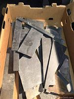 Box containing mostly angular, dark gray and black slate slabs of various sizes and thicknesses, flat pieces suitable for mosaic use.