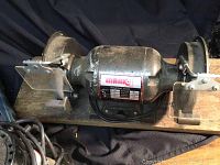 Marc 1 bench grinder mounted on wood base, showing grinding wheels and safety shields