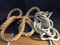 Four large pieces of rope including brown twisted, white twisted, white braided, and yellow synthetic ropes