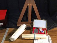 Wooden easel standing in back with calligraphy kit box, ink bottle, and paper rolls in front