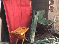 Photo showing two green fold-up camping chairs, a rolled green small raft bag, and a small wooden fold-up stool.
