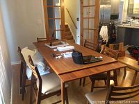 Table and six chairs assembled around in dining area, surface clutter present