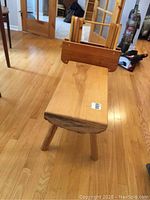 Side view of solid wooden bench showing natural wood slab seat with uneven natural edge and three round legs, detailed bottom visible.