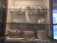 Full set displayed in cabinet with stacked plates, bowls, cups, mugs