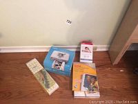 Canon Selphy CP720 printer box, Kodak photo paper, instruction booklet, and paper trimmer on wooden floor against wall.