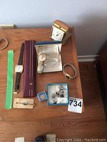 Three watches, two tie clips, cufflink cases and folding travel alarm clock on wooden surface