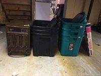 Kenmore 30 dehumidifier, black and green Rubbermaid bins and foldable black pet safety gate together on floor