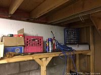 Wide shot of wooden shelf with assorted boxes, spray cans, and cables including WD-40 and an extension cord