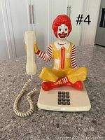 Front view of the seated Ronald McDonald figure holding the handset and showing the touch-tone keypad.