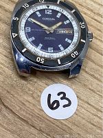 Front view of watch case and bezel without strap on wood surface