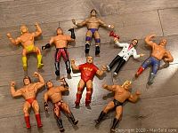 Nine vintage WWF wrestler figures in various poses and attire shown laid out on a floor.