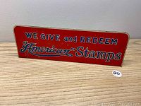 Front view of the red tin sign with white and blue text.