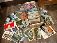 Wide view of cardboard box filled with postcards and scattered cards on floor