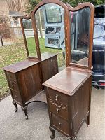 Full view of the wooden vanity showing the three-panel mirror and drawers on both sides.