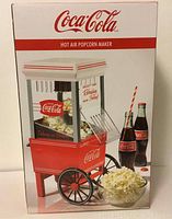 Front view of Coca Cola branded nostalgia hot air popcorn maker in box showing product design and branding.