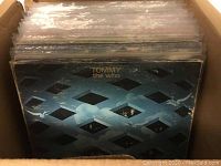 Box of vinyl records stored in plastic protective covers with visible album cover for Tommy by The Who