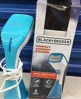 Blue BLACK+DECKER compact garment steamer standing upright next to the original box featuring product image and branding.