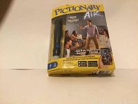 Pictionary Air game box with pen visible inside, showing front packaging with instructions and game images