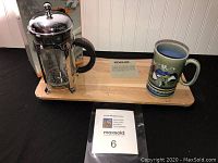 Full view of the lot showing the Starbucks French press, Kohler cutting board, and vintage farm print mug on a display surface.