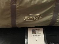 Close-up photo of the Evenflo brand logo on the olive green carrying bag for the playpen.
