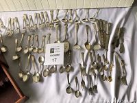 Full overview of the silver plated silverware laid out on white surface including forks, spoons, knives, serving pieces.