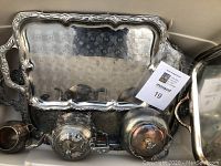 Top view showing large and smaller silver plated trays stacked and tea pots placed inside them