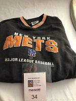 Front view of folded black vintage New York Mets sweatshirt with large orange and white lettering and MLB logo, including a MaxSold auction lot marker in photo.