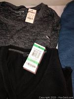 Grey and black sweaters stacked together showing tags and texture details