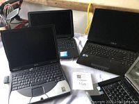 Four laptops displayed together showing various brands including Dell and Asus.