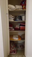 Full view of linen closet with shelves holding folded towels, linens, and paper products