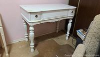 White wooden desk with curved front and fluted legs, three drawers with round metal handles, showing use wear