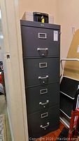 Full view of a black 4-drawer vertical file cabinet with label holders and silver handles