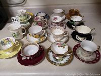 Top view of 14 assorted teacups with matching saucers in various floral and gold designs