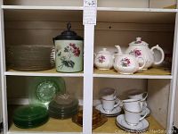 Overview of shelves showing most of the glass plates, biscuit jar, tea cups and tea pot.