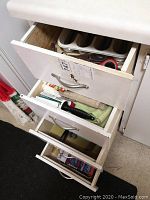 Lower drawers showing open boxes of food wrap products including aluminum foil and plastic wrap, with some additional kitchen cloths.