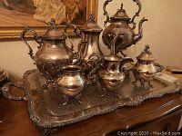 Full view of entire tea service on large ornate silver plated tray showing all items in the set, tarnished condition visible.