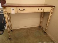 Front view of the console table showing single drawer, tapered fluted legs, and rectangular brass handles