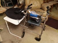 Photo showing black Sunbeam heating pad on white folding table next to a metal folding walker with basket and foam grips wrapped with blue tape.