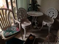 Overview showing bistro table, chairs, plastic chair, cushion, plant and planters