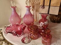 Two opalescent cranberry hobnail glass decanters with clear glass stoppers