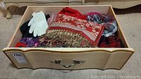Wide shot of wooden drawer with winter accessories including gloves, scarves and hats neatly arranged.