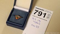Ring inside a blue jewelry box with MaxSold label showing note '14K ring w/stone size 5.5'